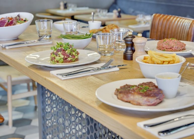Table en bois du restaurant Le Choupinet avec plusieurs plats froids et chauds