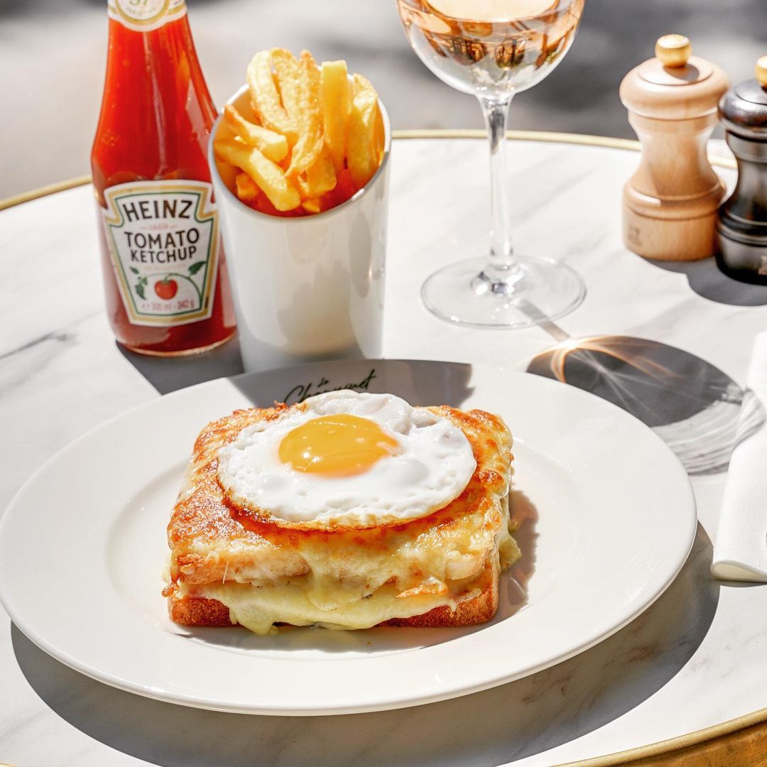 Croque Choupinette, croque-monsieur revisitée avec un œuf au plat dessus, une portion de frites maison, du ketchup, un verre de rosé, sel et poivre sur la terrasse du restaurant Parisien Le Choupinet